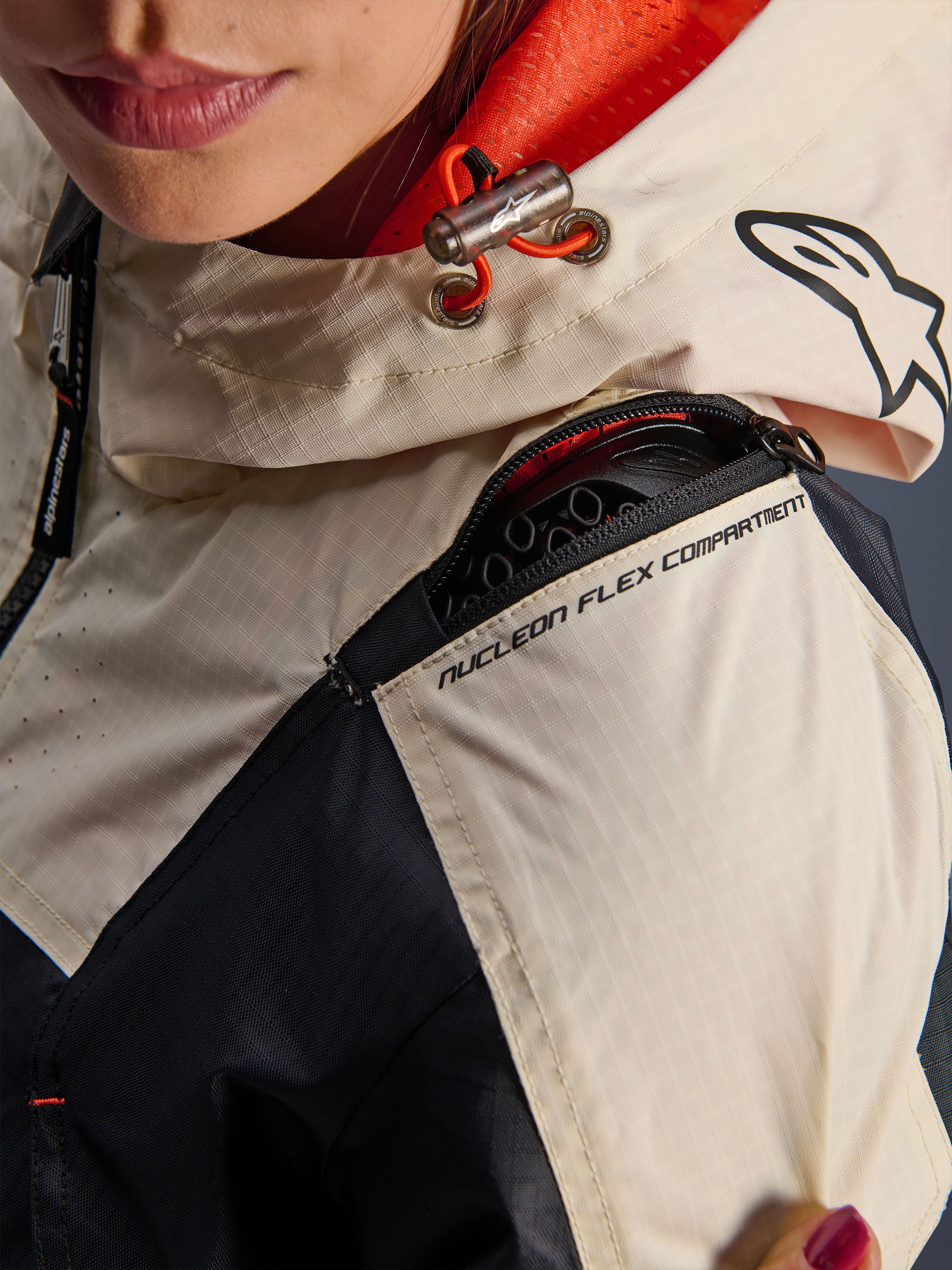 Alpinestars Molly Air-jakke, motorcykeljakke til damer, Black Almond, nærbillede af skulderen, der viser lynlåsen til Nucleon Flex-rummet, ripstop-stof og orange mesh-foring inde i hætten