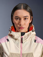 Nærbillede af en kvindelig model iført Alpinestars Molly Air Jacket i Sand Pink Almond, med høj krave og hætte med klart orange for, lyserød lynlås foran, ripstop-stof med laserperforeret bryst for ventilation, urbant motorcykelbeskyttelsesudstyr