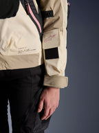 Alpinestars Molly Air-jakke, urban motorcykeljakke til kvinder, Sand Pink Almond, nærbillede fra siden, der viser ærmelomme med lyserødt logo, sort velcropatch og mærkets missionstekst på lænden, let ripstop-materiale