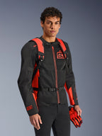 Alpinestars MM93 AMP3 rygsæk, rød fluo og sort, bæres af en model med en matchende sort og rød MM93 motorcykeljakke og handsker, set forfra med fokus på de justerbare skulderstropper og brystspænde, teknisk racing-inspireret udstyr