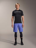 Alpinestars A-Aria Lite Short i Baja Blue, MTB-shorts til mænd, båret med en sort kortærmet jersey og beskyttende knæbeskyttere, med laserperforeringer til ventilation, mountainbike-performanceudstyr