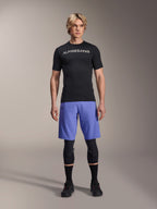 Alpinestars A-Aria Lite Short i Baja Blue, MTB-shorts til mænd, båret med en sort kortærmet jersey og beskyttende knæbeskyttere, med laserperforeringer til ventilation, mountainbike-performanceudstyr