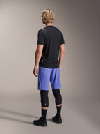 Mandlig model set bagfra iført Alpinestars A-Aria Lite Shorts i Baja Blue, kombineret med en sort kortærmet jersey og sorte knæbeskyttere, professionelt MTB-cykeltøj til trail-kørsel
