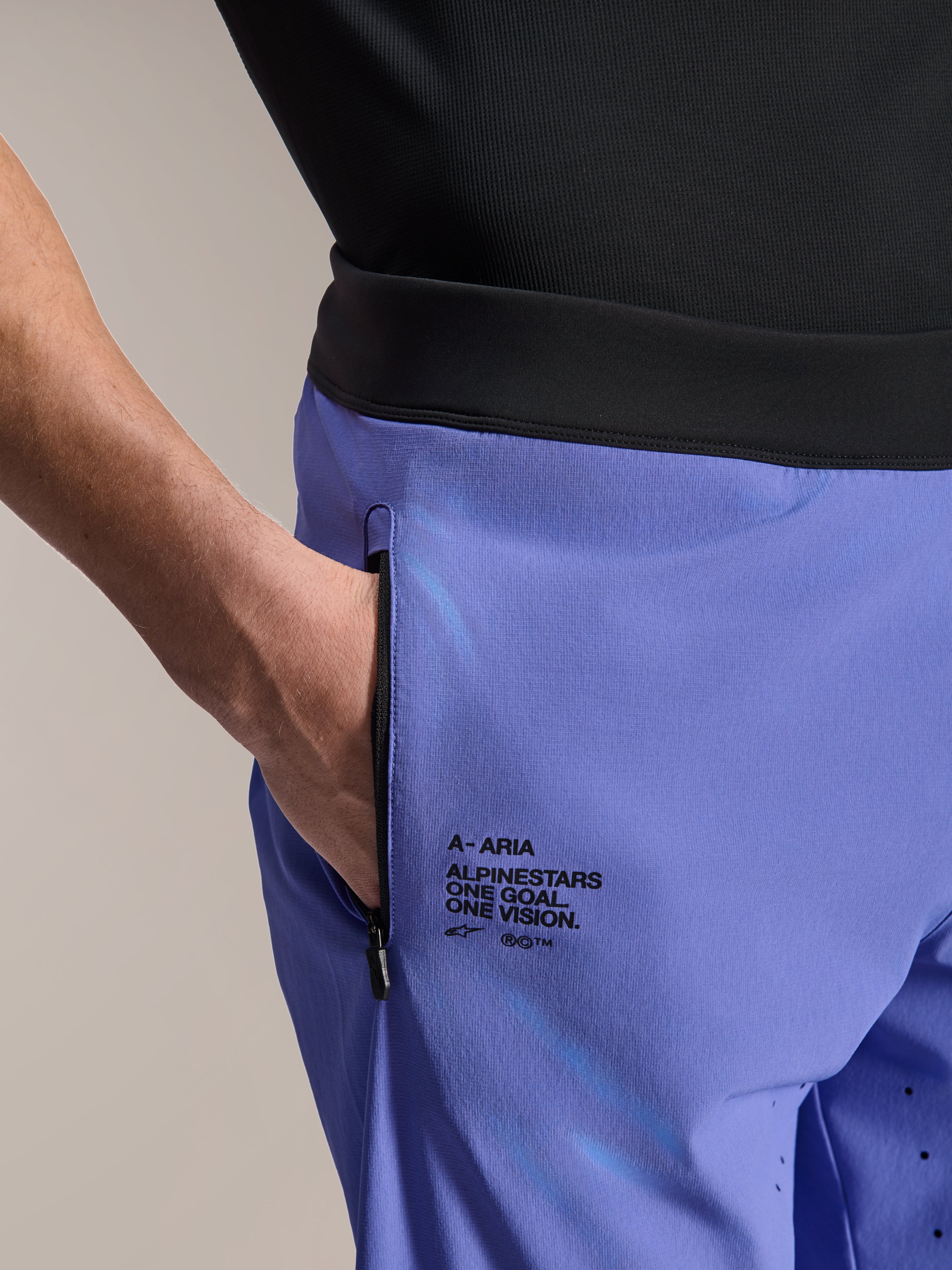 Alpinestars A-Aria Lite shorts, MTB-shorts, Baja Blue, nærbillede der viser forlomme med lynlås og branding på siden med teksten "One Goal. One Vision.", sort linning og teknisk stof til mountainbiking