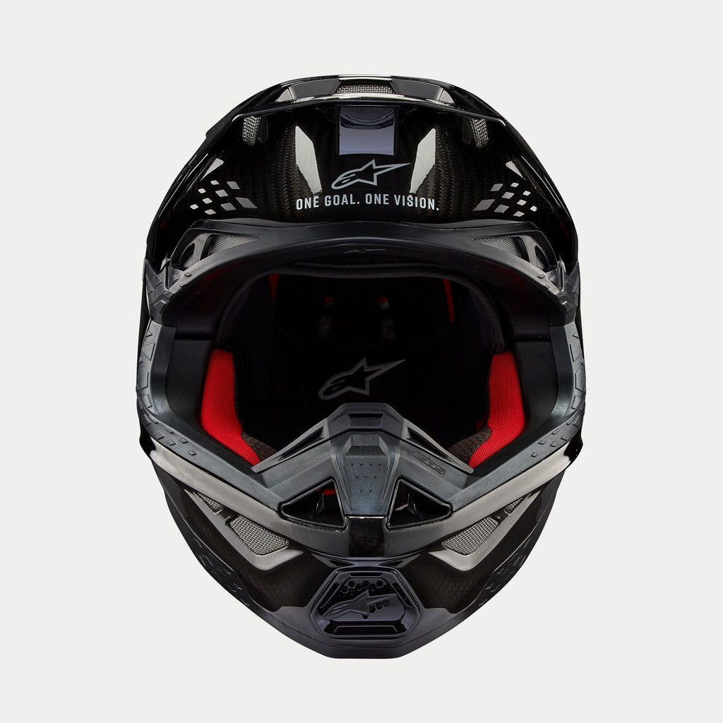 Alpinestars Supertech M10 Solid hjelm, motocrosshjelm, sort blank kulfiber, set forfra med rødt indvendigt for, kulfiberskal og "ONE GOAL. ONE VISION." slogan på visiret