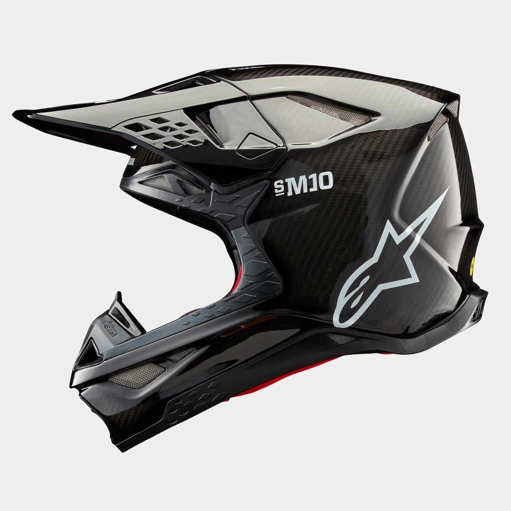 Alpinestars Supertech M10 Solid hjelm, motocrosshjelm, sort blank carbon, sideprofil med synlig kulfibervævning, hvidt SM10-logo og Alpinestars-logo, strømlinet aerodynamisk design med mesh-dækkede ventilationsåbninger