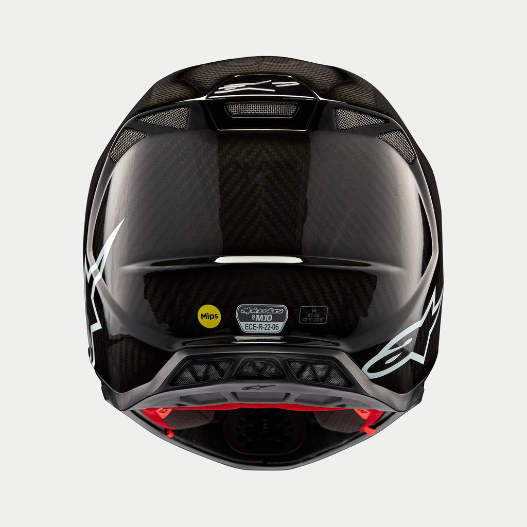 Alpinestars Supertech M10 Solid hjelm, sort blank kulfiber, set bagfra viser blank kulfibervævning, hvidt Alpinestars-logo, MIPS- og ECE-certificeringsmærkater, aerodynamisk form med ventilationsåbninger