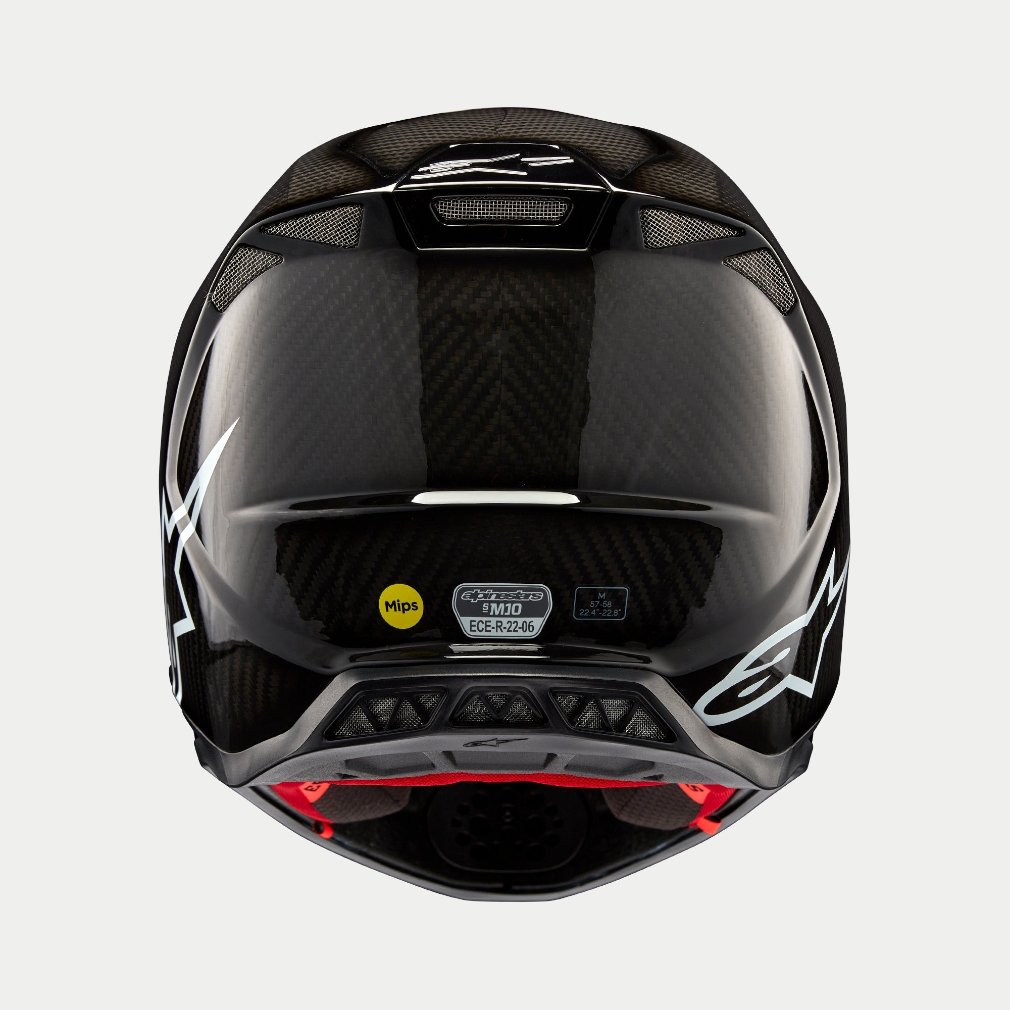 Alpinestars Supertech M10 Solid hjelm, sort blank kulfiber, set bagfra viser blank kulfibervævning, hvidt Alpinestars-logo, MIPS- og ECE-certificeringsmærkater, aerodynamisk form med ventilationsåbninger