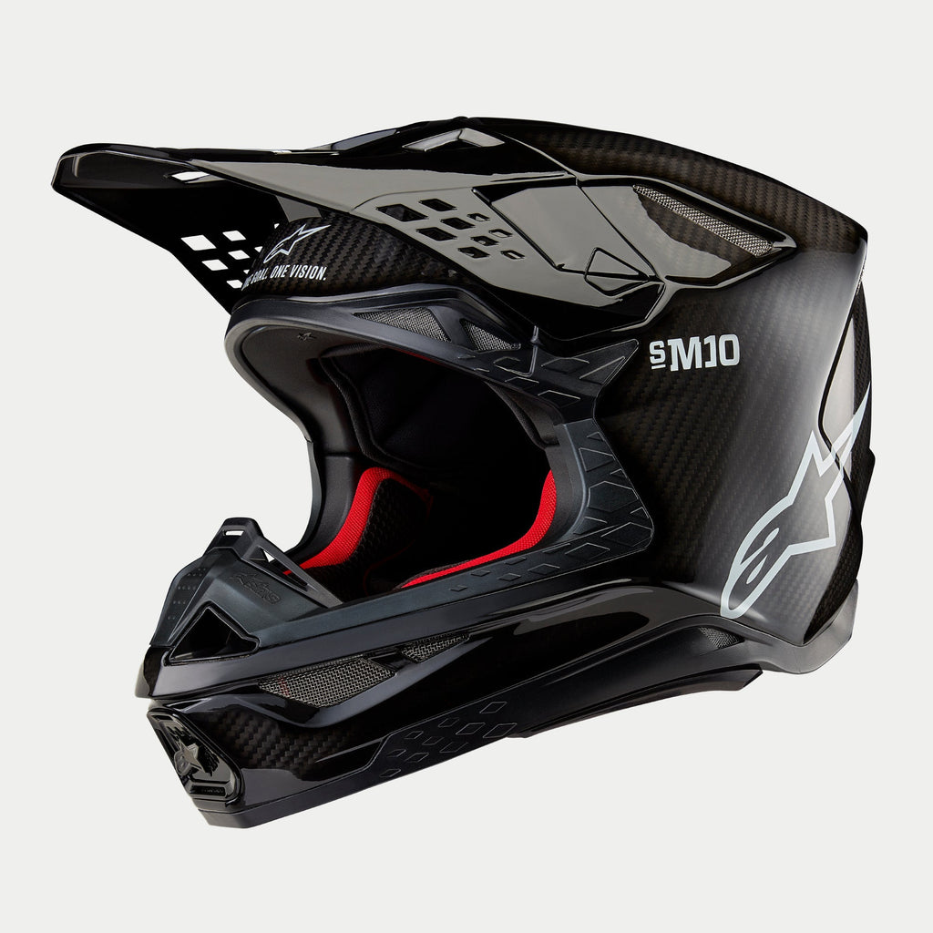 Alpinestars Supertech M10 Solid hjelm, motocross-hjelm, sort blank carbon med synlig fibervævning, hvidt Alpinestars-logo og SM10-branding, rød indvendig foring, aerodynamisk design med flere ventilationsporte