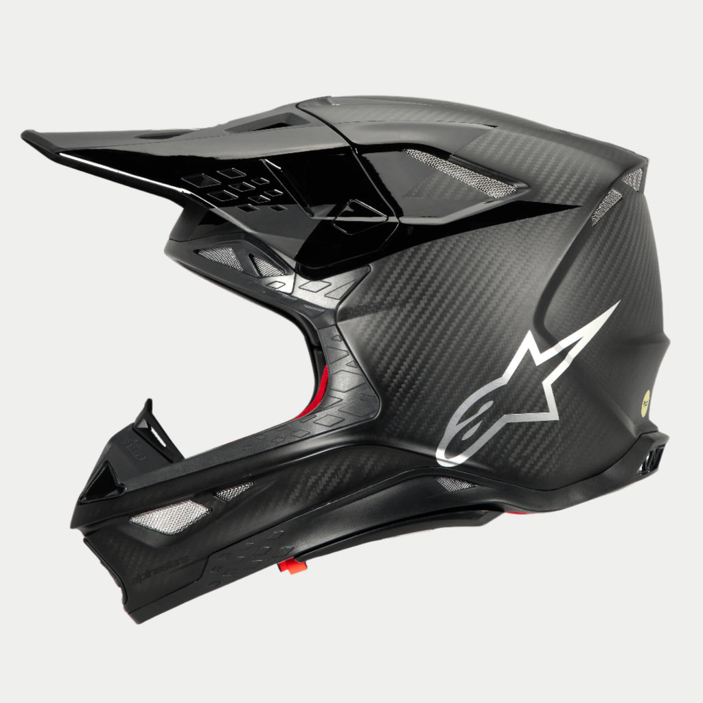 Alpinestars Supertech M10 Fame ECE 22.06 hjelm, sideprofil, mat og blank sort carbon-finish, med synlig kulfibervævning, sølvfarvet Astars-logo på siden, aerodynamisk design med integrerede ventilationsåbninger og sort visir