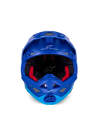 Alpinestars Supertech M10 Flood-hjelm ECE, motocross-hjelm, metallisk og mellemblå med sorte carbon-detaljer, set forfra viser hagebeskytter og synsfelt, hvide Alpinestars-logoer og tekst, rød indvendig polstring, professionel off-road-beskyttelse