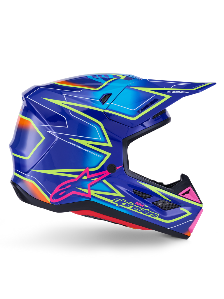 Alpinestars S-M7 Cast hjelm, motocross-hjelm, blå, pink og gul fluo blank, sideprofil med markante geometriske mønstre, pink Alpinestars-logo og ventileret aerodynamisk skal.