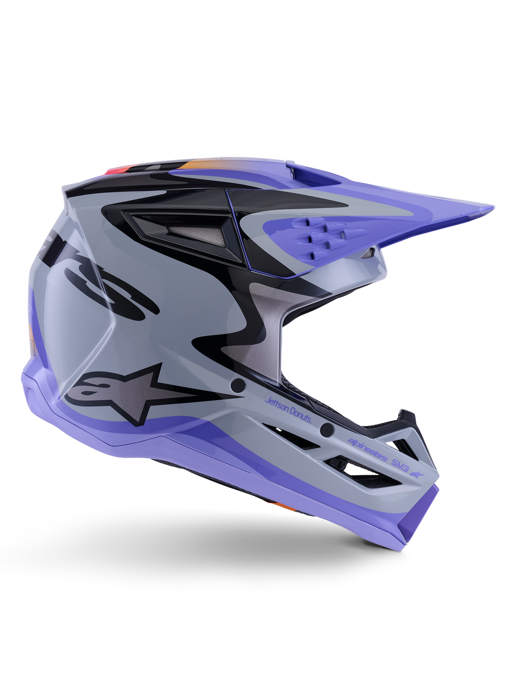 Alpinestars S-M3 Jettson ungdomshjelm, motocross-hjelm, grå, lilla og sort i blank finish, sideprofil med skarp, kantet grafik og 'Jettson Donuts'-branding, aerodynamisk skaldesign med ventilationsporte og Alpinestars-logo, højtydende terrængående beskyttelsesudstyr til unge