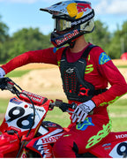 Motocrosskører iført Alpinestars A-5 Plasma brystbeskytter i sort og rød, kombineret med en rød og limegrøn racingtrøje og bukser, siddende på en rød Honda-motorcykel, højtydende off-road beskyttelsesudstyr