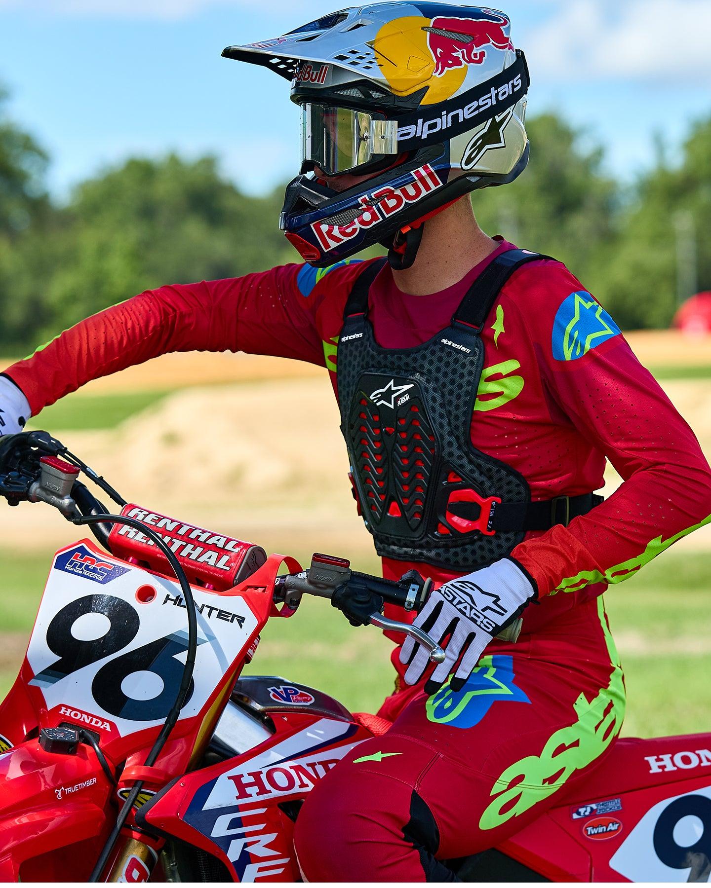 Motocrosskører iført Alpinestars A-5 Plasma brystbeskytter i sort og rød, kombineret med en rød og limegrøn racingtrøje og bukser, siddende på en rød Honda-motorcykel, højtydende off-road beskyttelsesudstyr
