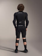 Alpinestars A-Impact Plasma Beskyttelsesjakke - Langærmet, set bagfra, sort med hvide Alpinestars-logoer, båret med beskyttelsesshorts og knæbeskyttere for fuld kropsbeskyttelse til mountainbike