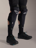 Alpinestars A-Impact Plasma Pro knæbeskyttere, sort og hvid, med Nucleon PLASMA-teknologi branding, båret med sorte strømper og sorte mountainbike-sko, sikre velcrostropper, ergonomisk beskyttelsesudstyr til off-road cykling