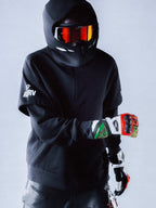 Alpinestars RSRV Vault Hoodie, sort hættetrøje, person iført motorcykelhjelm med reflekterende rød-orange visir, farverige handsker, sort beskyttelsesudstyr, moderne streetwear design med hvide logoer på ærmet
