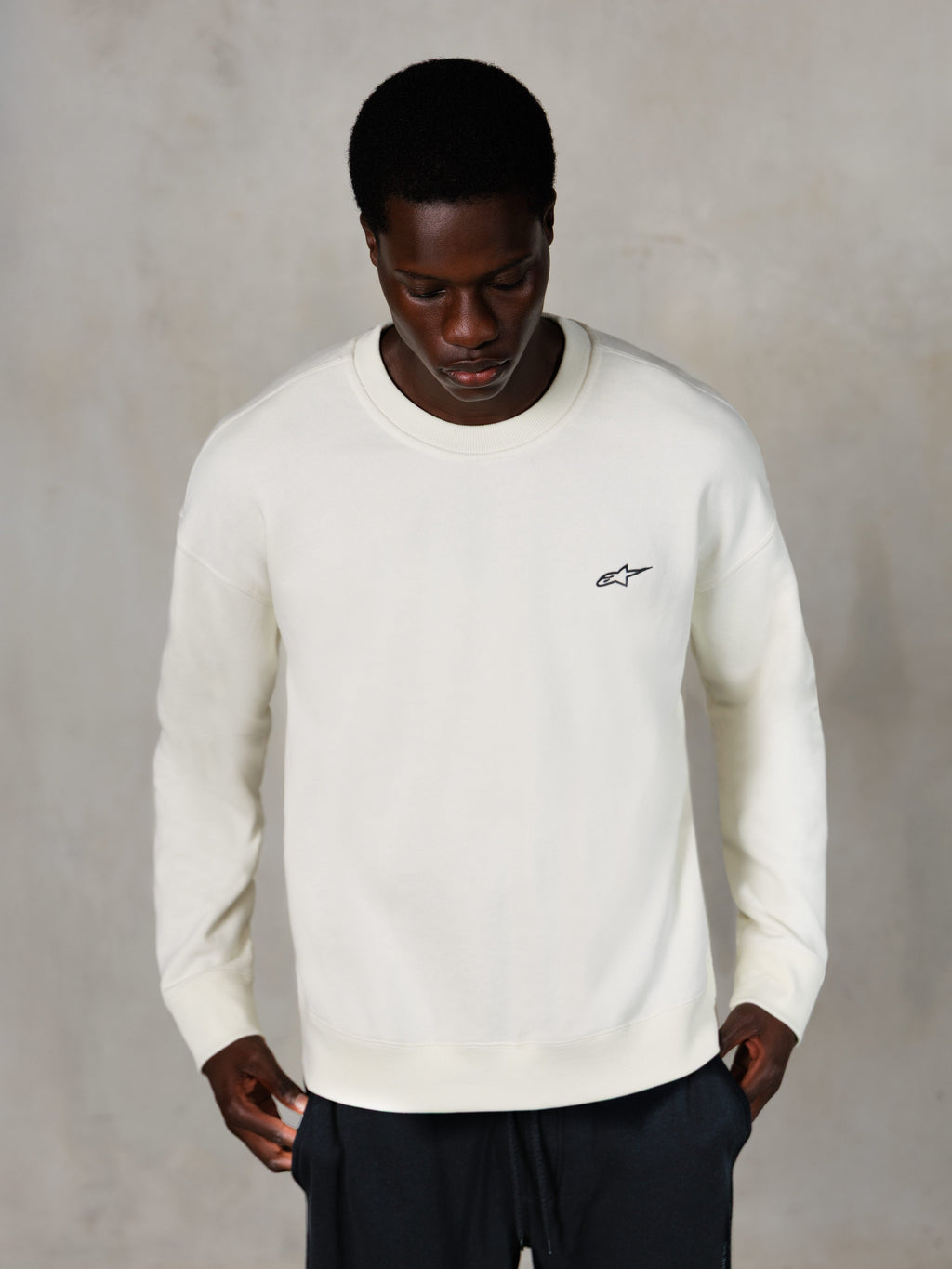 Alpinestars Essentials Ageless Crew, crewneck sweatshirt, off-white, lille sort Alpinestars-logo på brystet, båret af model, afslappet lifestyle streetwear, premium blød fleece