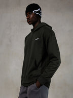Alpinestars Essentials Ageless Hoodie, Off Black, mandlig model iført afslappet streetwear, mørk koksgrå stenvasket fleece med et lille hvidt stjerne-logo, kombineret med en sort Alpinestars beanie og grå bukser