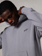 Alpinestars Essentials Ageless Hoodie, Silver, nærbillede af en mand, der justerer hætten på den grå hættetrøje, lille sort Alpinestars-logo på brystet, førsteklasses motorsportsinspireret fritidstøj