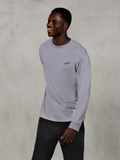 Alpinestars Essentials Ageless LS Tee, langærmet t-shirt, sølv, lille sort logo på brystet, båret af en smilende model med mørke bukser, afslappet moderne pasform, afslappet motorsport-livsstilstøj