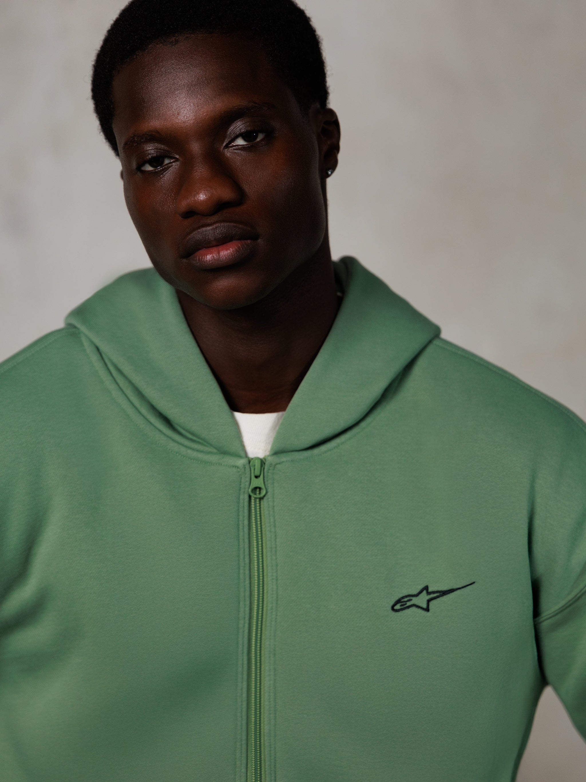 Alpinestars Essentials Ageless Zip Hoodie, livsstilsportræt, kaktusgrøn med lille sort logo, lynlås foran, blød fleecetekstur, afslappet motorsport-inspireret streetwear