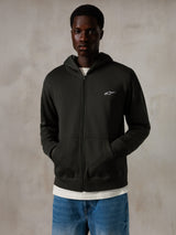 Alpinestars Essentials Ageless Zip Hoodie, Off Black, hættetrøje med gennemgående lynlås og et lille hvidt Alpinestars-logo på brystet, afslappet pasform, båret af en model med blå jeans og hvid t-shirt, afslappet motorsport-inspireret streetwear
