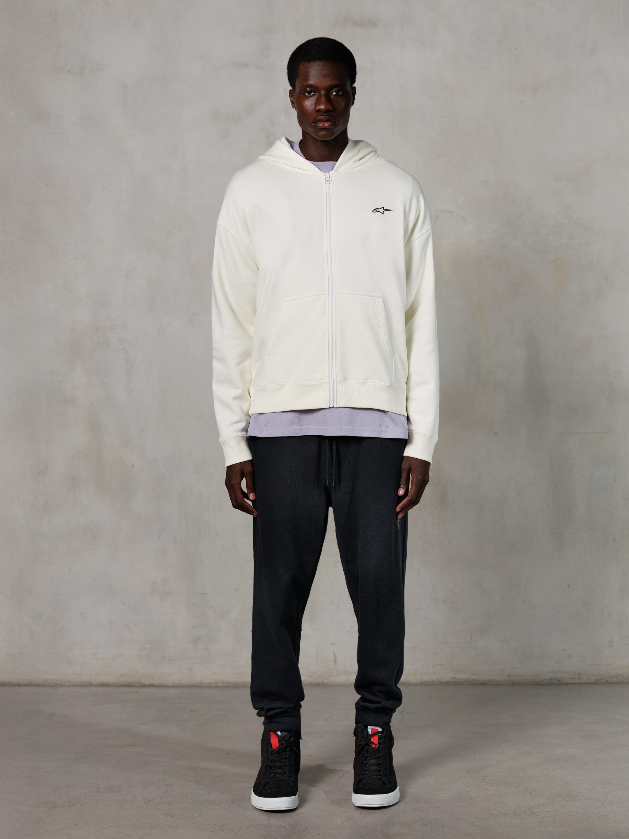 Alpinestars Essentials Ageless Zip Hoodie, casual streetwear, off-white with subtle black chest logo, full-zip front, hooded design, relaxed fit, styled with black sweatpants and sneakers