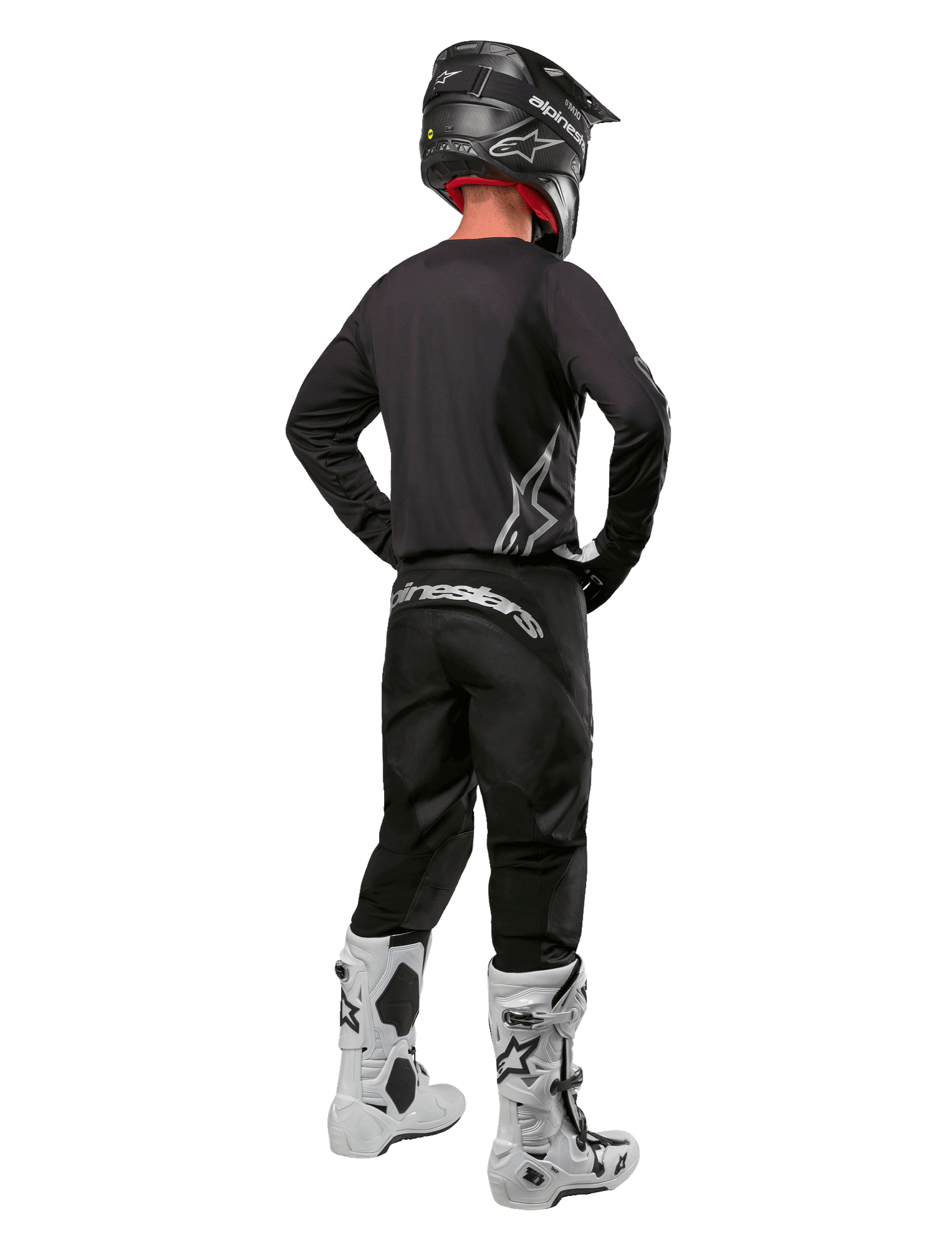 Alpinestars 2024 Fluid Graphite-gearsæt, motocross-kører set bagfra, grafitgrå jersey og bukser med sølvfarvet Alpinestars-branding, sort hjelm og hvide motocross-støvler, udstyr med atletisk pasform til off-road-kørsel