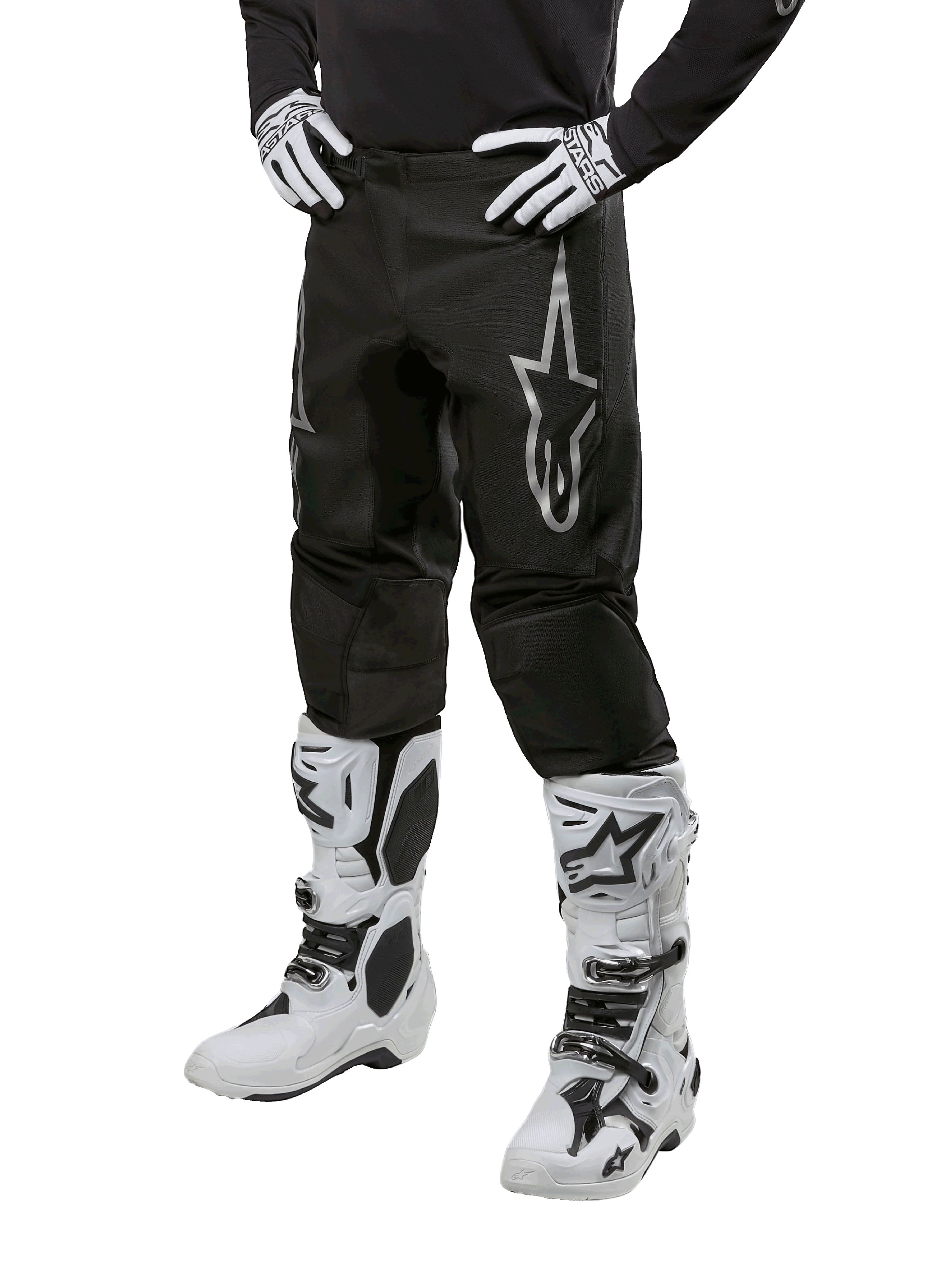 Alpinestars 2024 Fluid Graphite bukser, motocrossbukser, grå og sort, båret med hvide og sorte motocrossstøvler og handsker, med et stort sølvfarvet Alpinestars-logo på låret, atletisk sportspasform til off-road kørsel