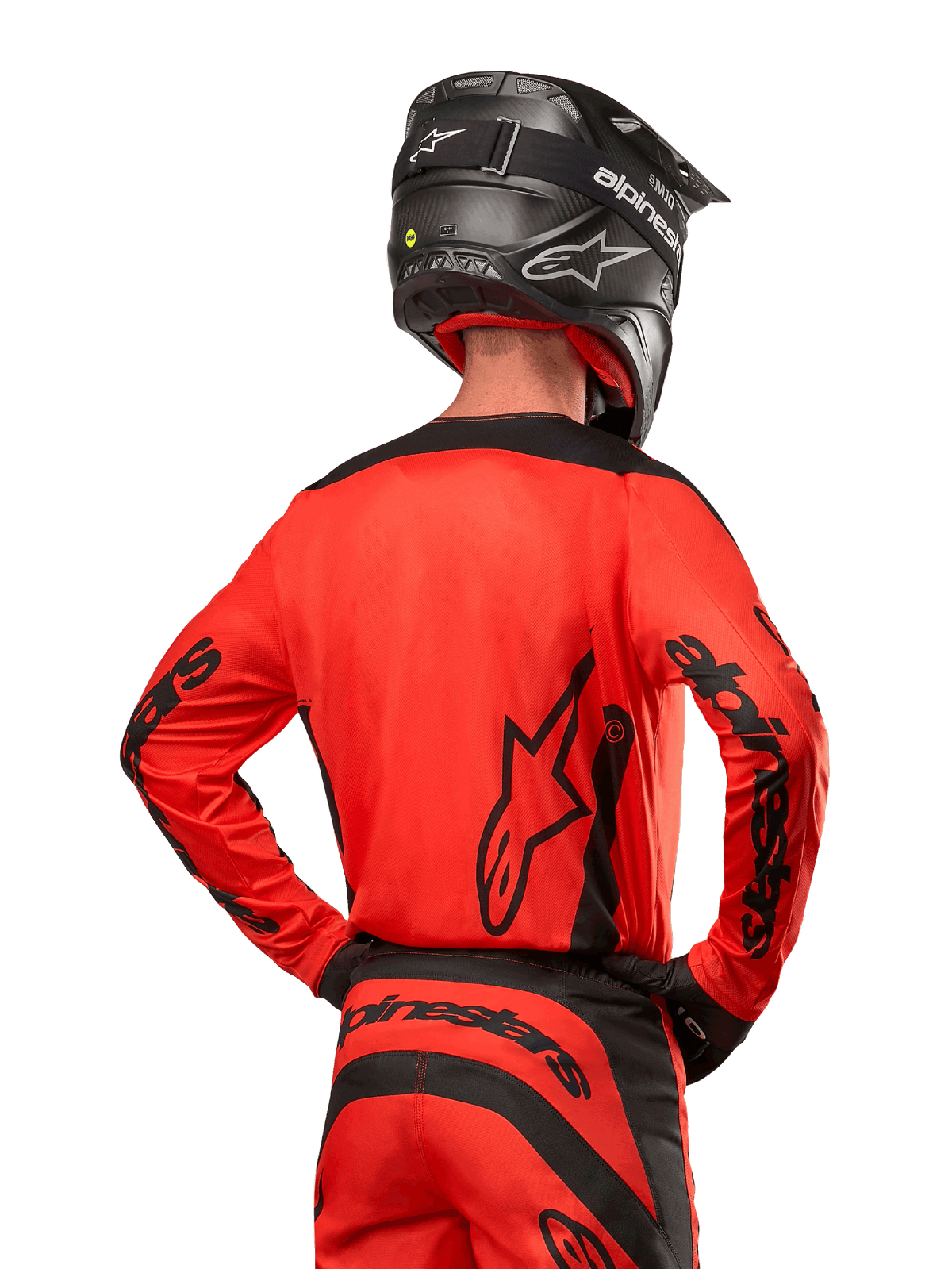 Motocrossrytter set bagfra iført Alpinestars 2024 Fluid Lurv trøje i Hot Orange og sort, med markant Alpinestars-branding på ryggen og ærmerne, kombineret med matchende motocrossbukser og en sort hjelm, designet til off-road racing.