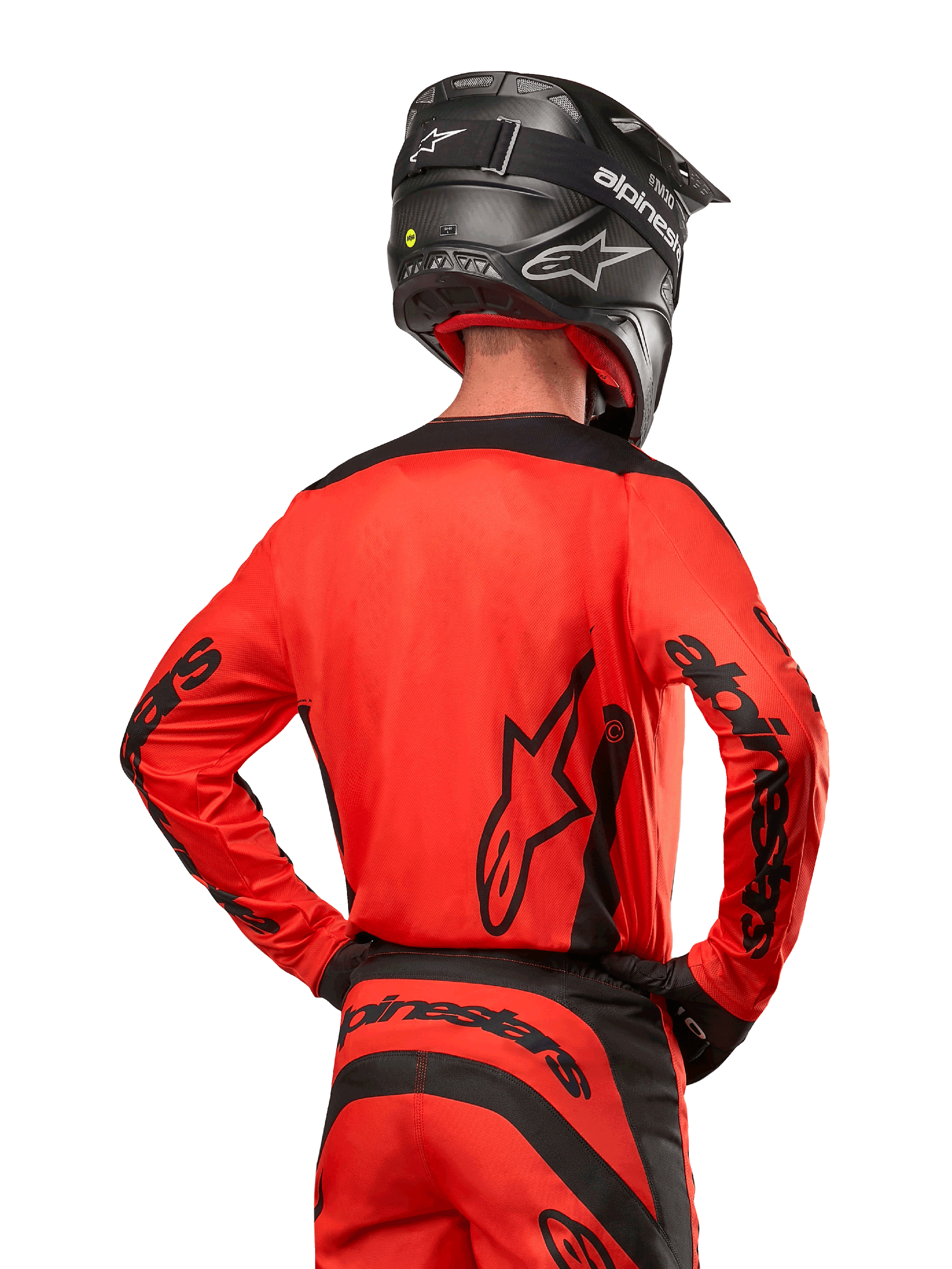 Motocrossrytter set bagfra iført Alpinestars 2024 Fluid Lurv trøje i Hot Orange og sort, med markant Alpinestars-branding på ryggen og ærmerne, kombineret med matchende motocrossbukser og en sort hjelm, designet til off-road racing.