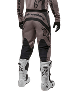 Alpinestars 2024 Fluid Lurv-bukser, motocross-bukser, Mud Black, set bagfra med stort sort Alpinestars-logo på bagen og sorte lægpaneler, båret med hvide og sorte motocross-støvler og matchende trøje.