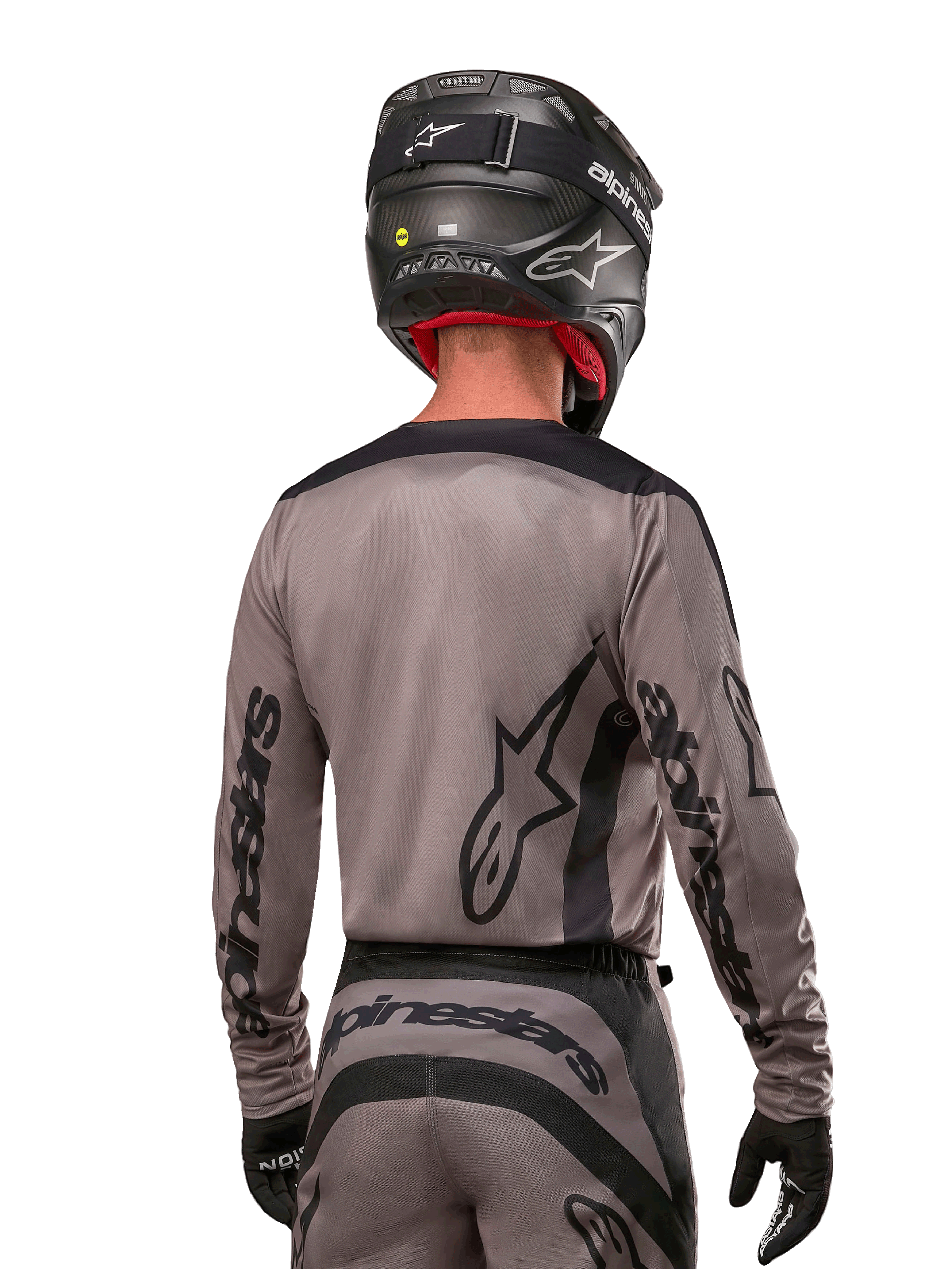 Motocross rider viewed from the back wearing the Alpinestars 2024 Fluid Lurv Jersey in Mud Black, featuring black Alpinestars branding on sleeves and back, paired with a black helmet and matching gear for off-road racing
