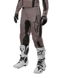 Alpinestars 2024 Fluid Lurv bukser, motocross-bukser, Mud Black og sort, med Alpinestars-logo, vist med sorte handsker og hvide motocross-støvler, sporty design til terrænkørsel