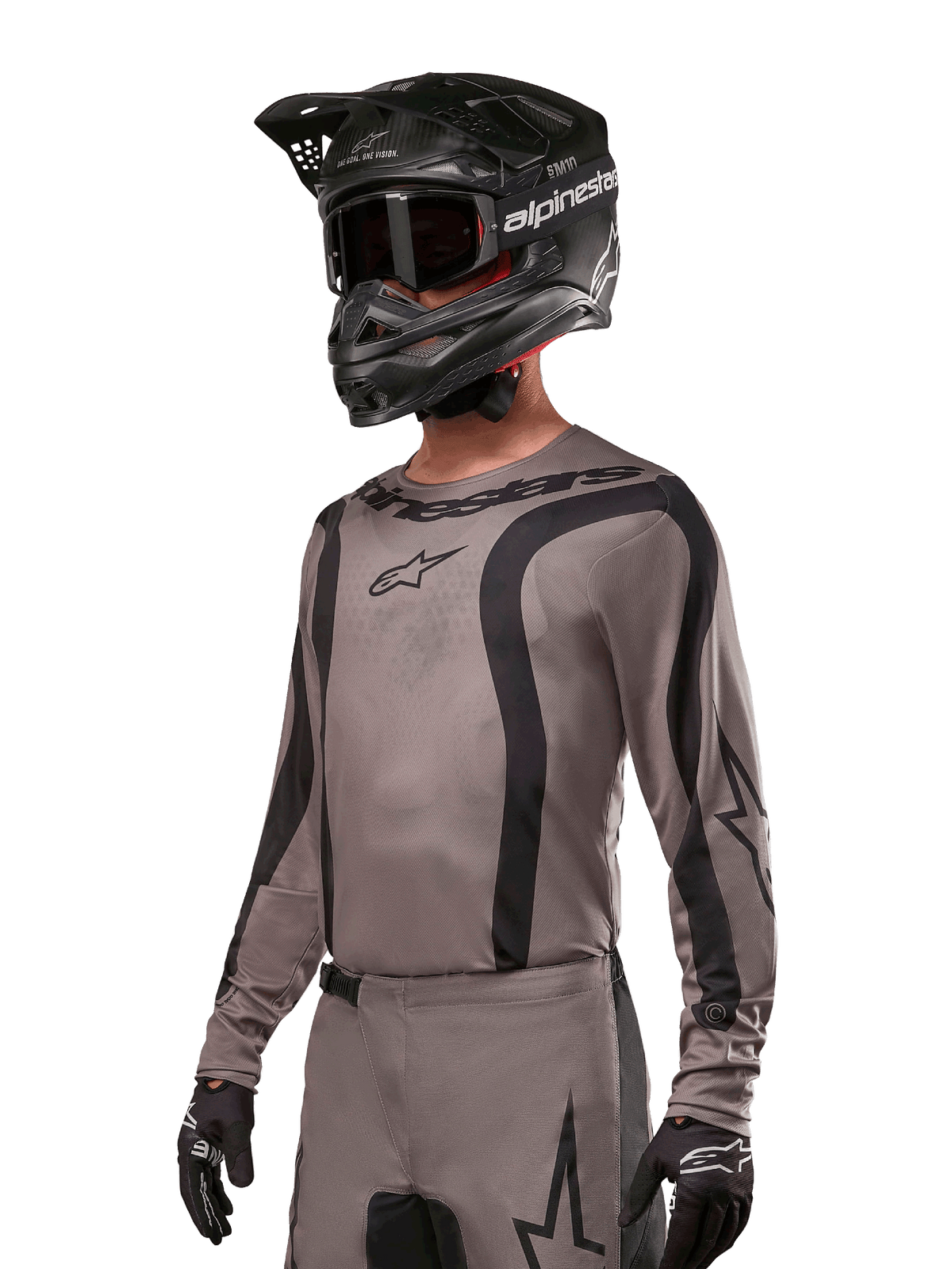 Alpinestars 2024 Fluid Lurv Jersey, motocross-trøje, Mud Black og grå, langærmet design med buede sorte striber og logoer, båret med matchende bukser og en sort motocrosshjelm, koordineret off-road racing-sæt