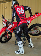 Alpinestars 2025 Fluid Haul udstyrssæt, sort og rød motocrosstrøje og bukser, kører 96 med motocrosscykel.