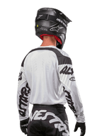 Alpinestars 2024 Racer Hana trøje, hvid og sort, set bagfra med ergonomisk pasform og markant branding på ærmerne, kombineret med en sort motocrosshjelm og matchende sort-hvide bukser, højtydende racerudstyr til terrænkørsel