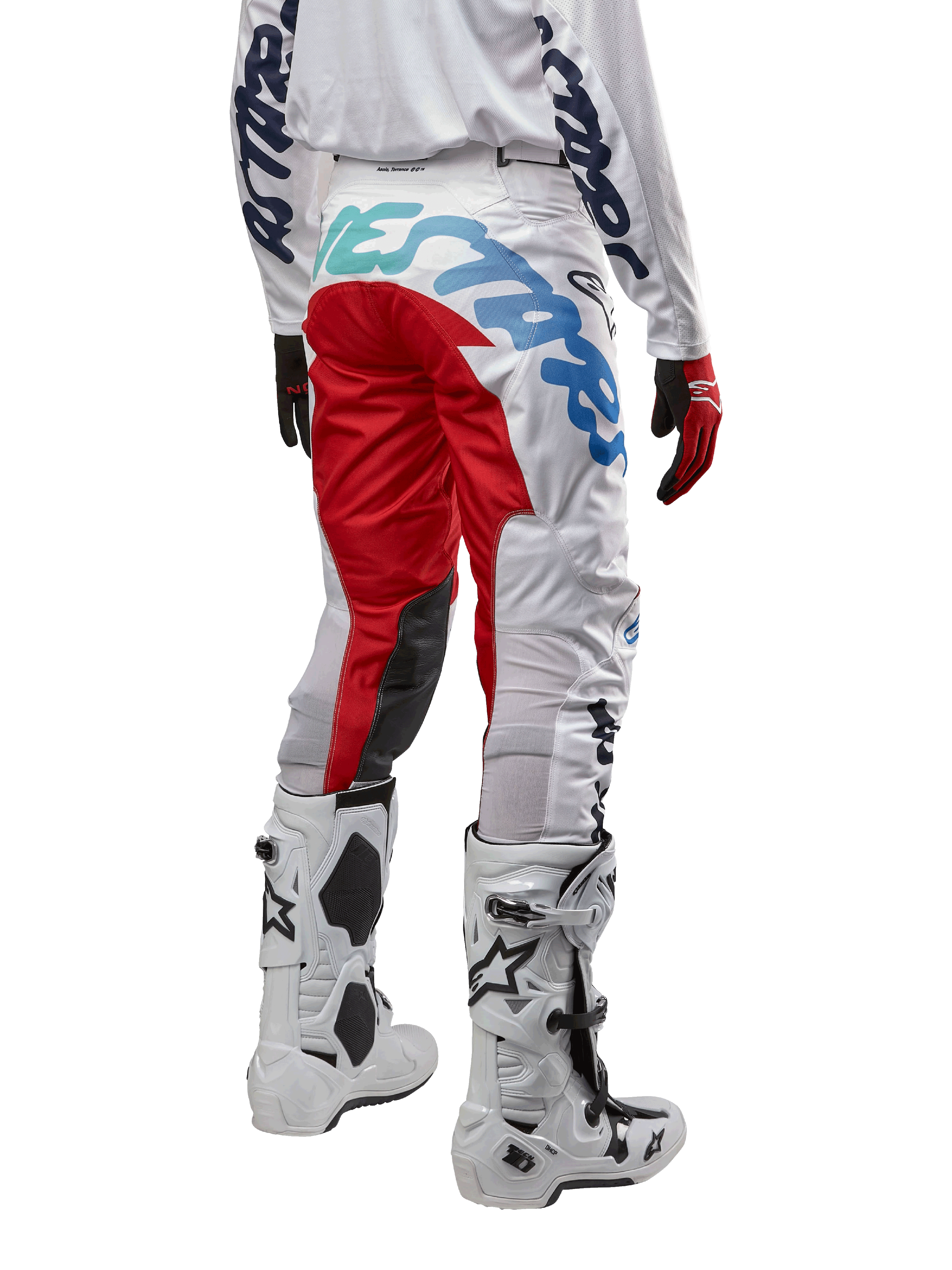 Alpinestars 2024 Racer Hana bukser, motocrossbukser, hvid flerfarvet med røde og blå accenter, set bagfra med stort branding på sædet, båret med hvide og sorte motocrossstøvler, designet til off-road ydeevne og holdbarhed