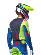 Alpinestars motocrosskører iført 2024 Racer Hoen trøje i Yellow Fluo og Blue Night Navy, med et rødt stjernelogo på ryggen, matchende motocrossbukser og en koordineret racinghjelm, set bagfra, der fremviser det ergonomiske design til off-road kørsel