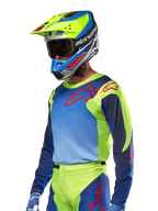 Alpinestars 2024 Racer Hoen Jersey, motocross trøje, neongul og mørkeblå med røde logoer, båret med en matchende gul, blå og rød hjelm og blå handsker, iøjnefaldende udstyr til terrænkørsel