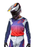 Alpinestars 2024 Racer Hoen Jersey, motocross-trøje, gradient i lilla og stærk orange med mørkeblå ærmer og lysegrå skulderpaneler, båret med matchende racerbukser og hjelm, komplet off-road køreudstyr