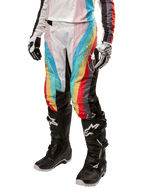 Alpinestars Stella 2024 Techstar bukser til damer, motocross-bukser, sort multicolor med diagonale røde, gule og blå striber, båret med sorte kørestøvler og hvide handsker, med beskyttende sorte knæpaneler og markant branding til off-road racing.