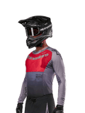 Alpinestars 2024 Supertech Dade trøje, motocross-jersey, rød og grå, langærmet med laserskårne perforeringer, båret af kører med sort hjelm og handsker, professionel atletisk racing-pasform