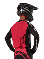 Alpinestars 2024 Supertech Ward Jersey, Motocross Jersey, Black and Red Berry, back view showing red mesh panel and black sleeves with white branding, worn with a black carbon fiber helmet and gloves, athletic race fit for off-road riding
