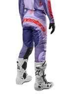 Alpinestars 2024 Techstar Ocuri bukser, motocross off-road bukser, lilla med kraftige orange detaljer, set bagfra, hvide Tech 10 støvler, professionelt racingudstyr til terrænkørsel