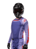 Alpinestars 2024 Techstar Ocuri Jersey, motocross racingtrøje, lilla og stærk orange, langærmet med laser-skårne perforeringer for ventilation, atletisk race-pasform, vist med sort motocrosshjelm og sorte handsker
