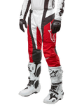 Alpinestars 2024 Techstar Ocuri bukser, motocross-racerbukser, Mars rød, hvid og sort, båret med matchende hvid og sort trøje, sorte handsker og hvide racerstøvler med spænder, teknisk beskyttelsesudstyr vist på en hvid baggrund