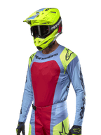 2024 Techstar Ocuri Jersey, Motocross Racing Jersey, Light Blue with Red and Fluo Yellow accents, worn with matching neon yellow helmet and black goggles, featuring black Alpinestars logos on chest and shoulders, athletic race-inspired design for off-road performance